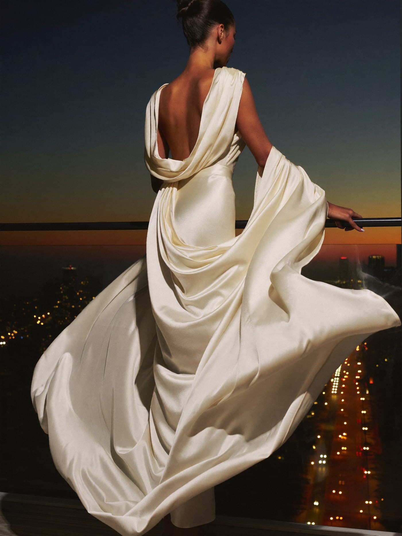 A woman in an ivory silk gown at a Miami balcony at dusk